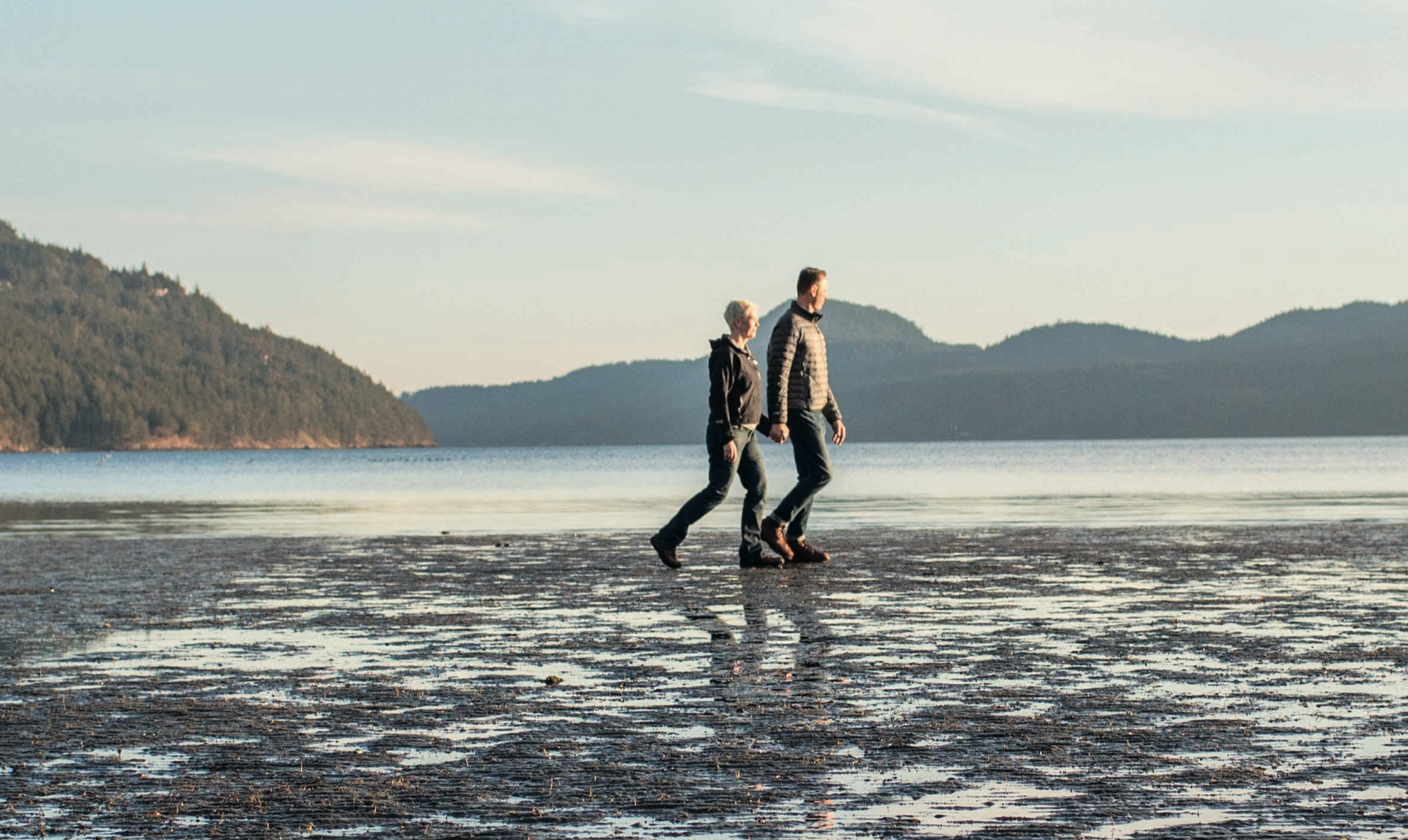 A couple walks along the shore, appreciating the nice view of nature