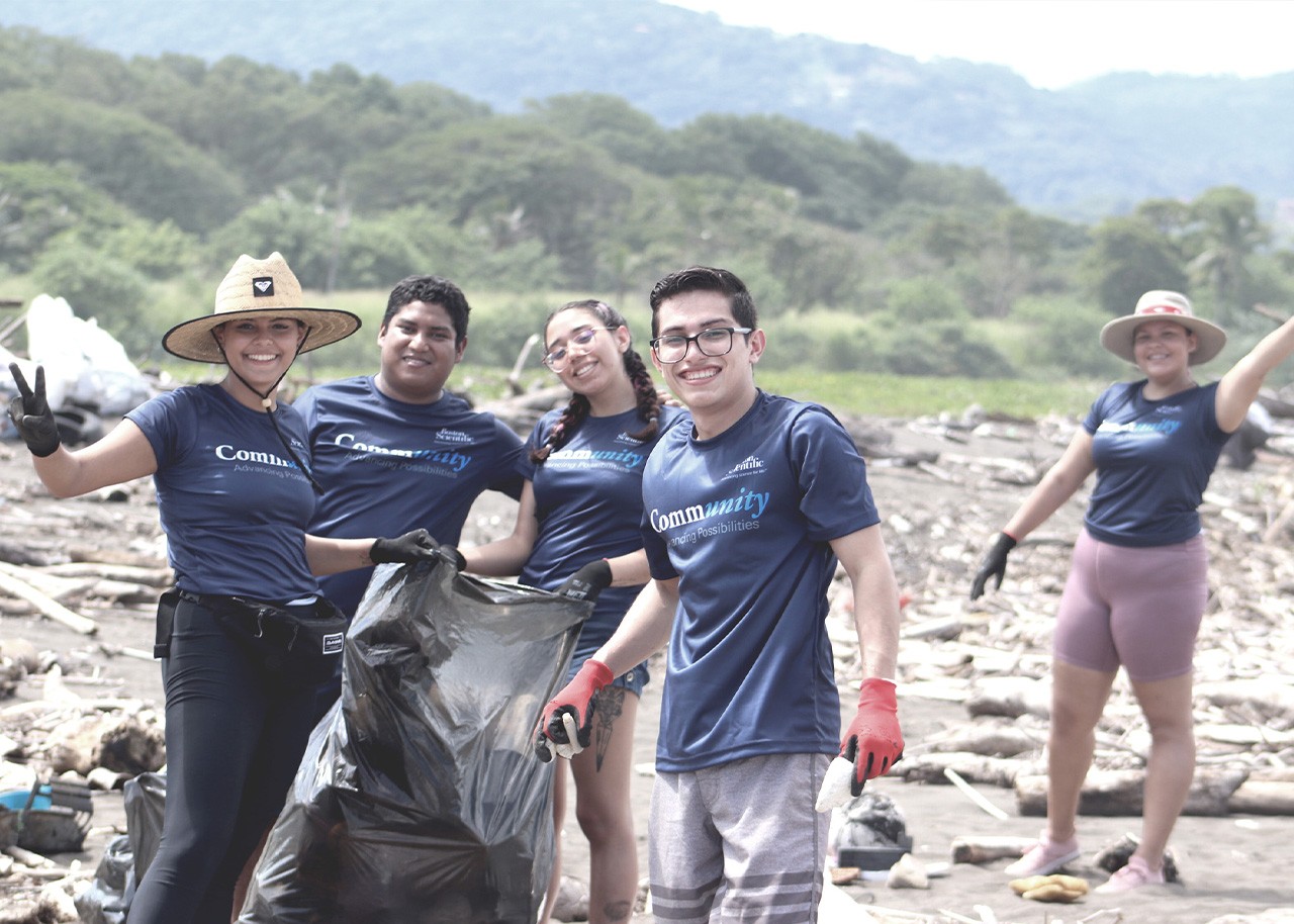 Employees wearing Boston Scientific t-shirts and holding a garbage bag while collecting waste.
