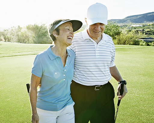 Elderly couple laughing and golfing in the sunshine.