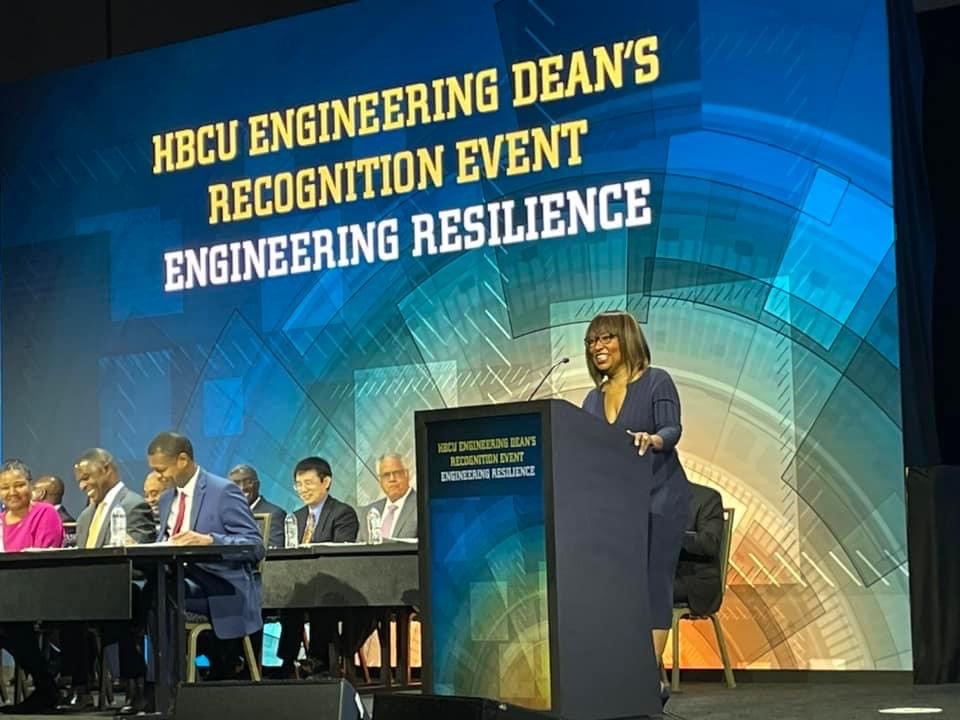 Camille Chang Gilmore stands at a podium onstage while giving a speech at an HBCU engineering event. 