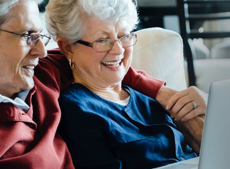 Older couple smiling and looking at a laptop