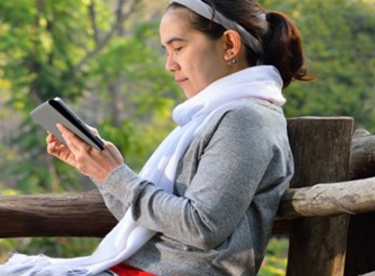 Woman sitting on a bench reading from her tablet