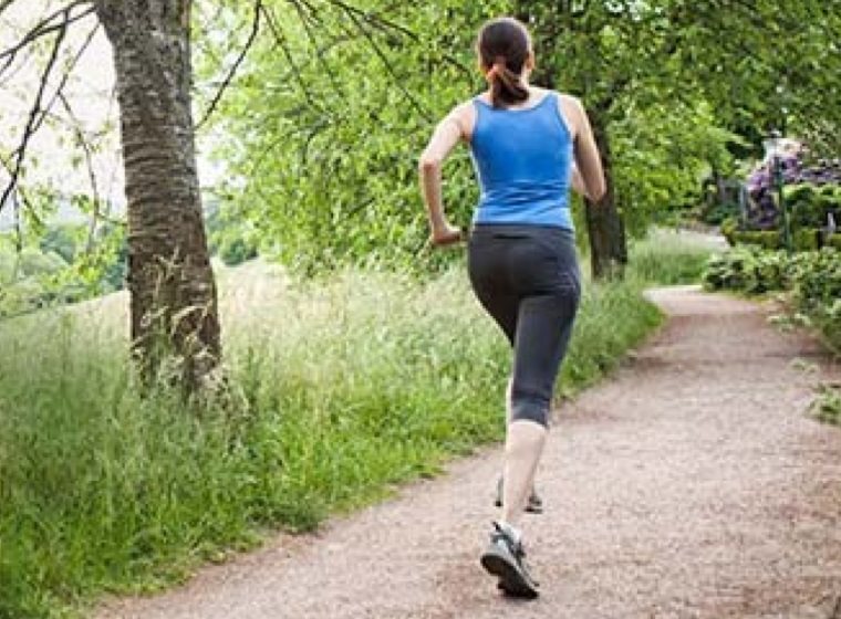 Woman exercising by running on a path in the outdoors