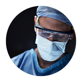 Physician wearing scrubs, mask and goggles.